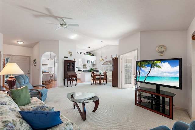 carpeted living room featuring a textured ceiling, vaulted ceiling, and ceiling fan