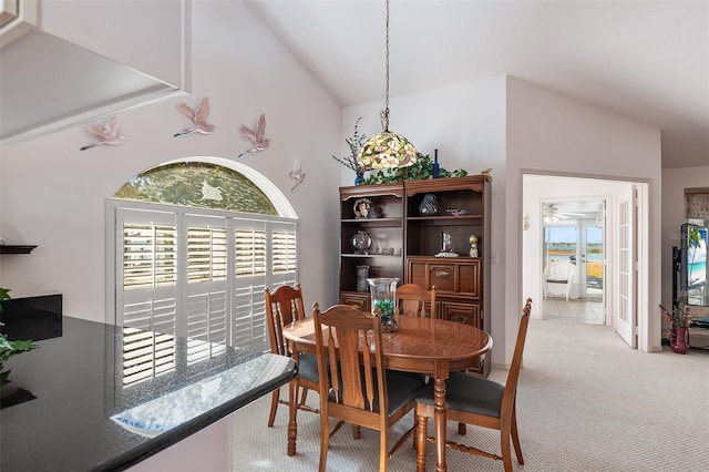 carpeted dining area featuring high vaulted ceiling