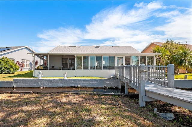 rear view of property with a sunroom and a lawn