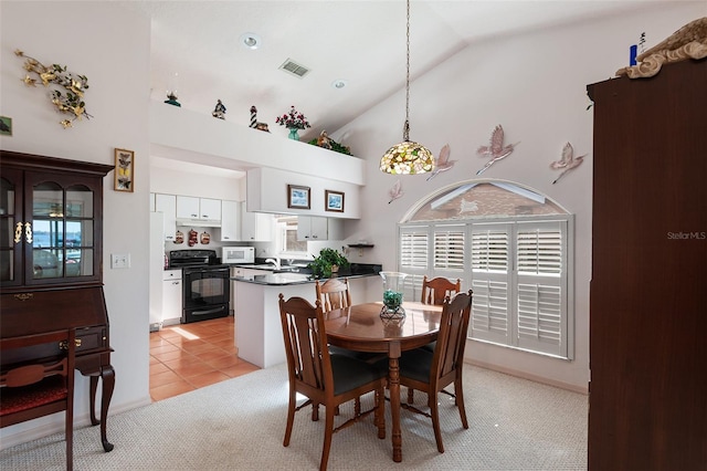 carpeted dining room featuring high vaulted ceiling