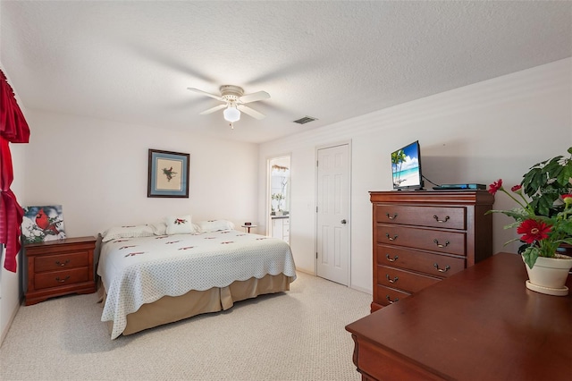 carpeted bedroom featuring ceiling fan and a textured ceiling