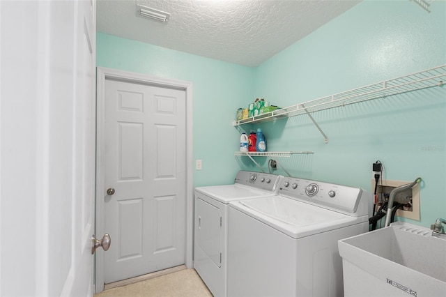 laundry room with independent washer and dryer, sink, and a textured ceiling