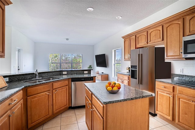 kitchen with light tile patterned flooring, sink, a center island, dark stone countertops, and appliances with stainless steel finishes