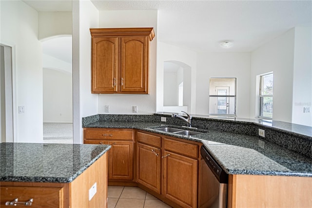 kitchen with light tile patterned flooring, sink, dark stone countertops, and kitchen peninsula