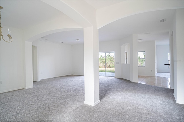 unfurnished room with light colored carpet and a notable chandelier