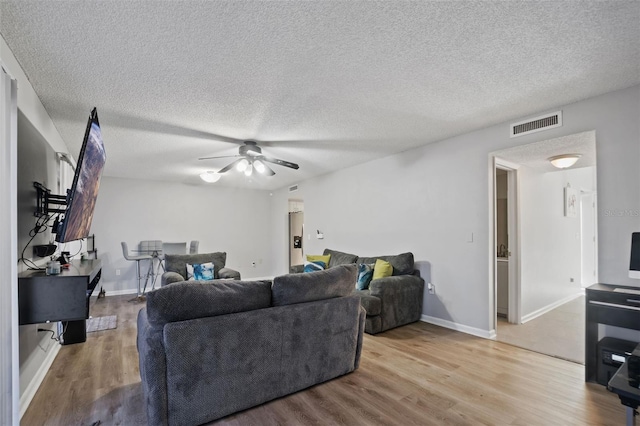 living room featuring ceiling fan, a textured ceiling, and light hardwood / wood-style floors