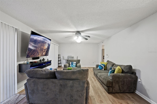 living room featuring ceiling fan, light hardwood / wood-style floors, and a textured ceiling