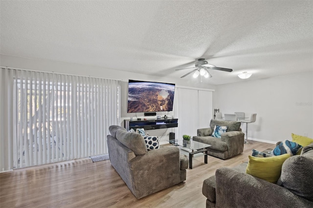 living room featuring ceiling fan, a textured ceiling, and light hardwood / wood-style flooring