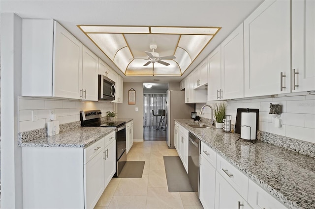 kitchen featuring white cabinetry, sink, ceiling fan, light stone counters, and stainless steel appliances