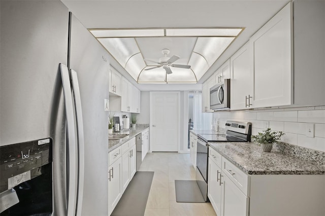 kitchen featuring white cabinetry, light tile patterned floors, appliances with stainless steel finishes, ceiling fan, and light stone countertops