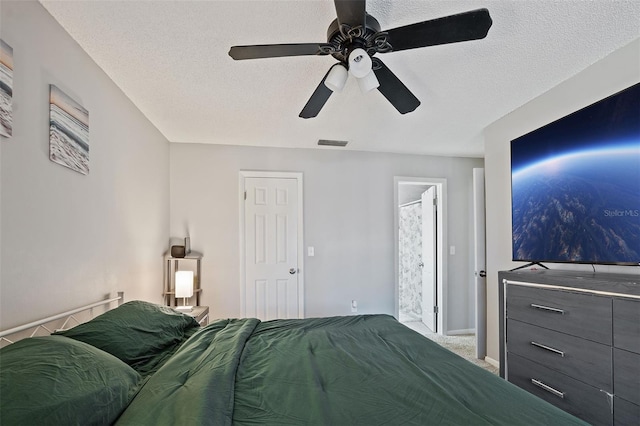 carpeted bedroom featuring ceiling fan and a textured ceiling