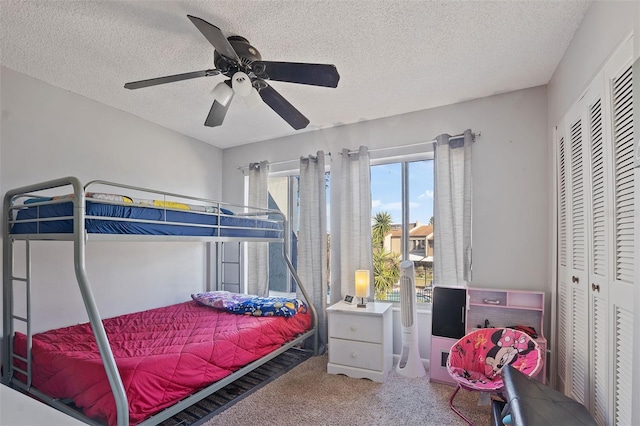 bedroom featuring a textured ceiling, carpet floors, a closet, and ceiling fan