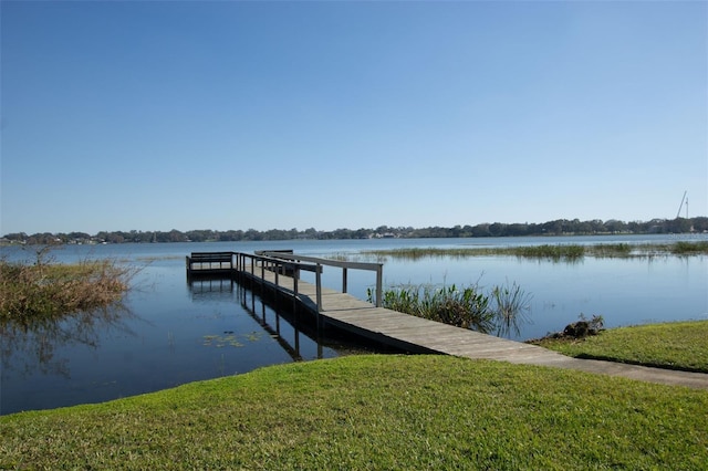 view of dock with a water view and a lawn