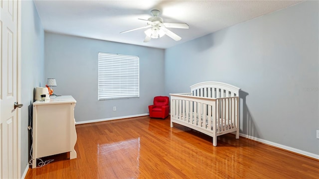 bedroom featuring ceiling fan, a nursery area, and light hardwood / wood-style floors