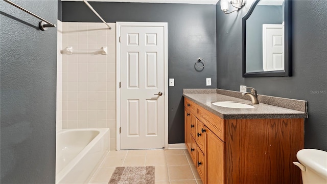 full bathroom featuring tile patterned flooring, vanity, tiled shower / bath, and toilet