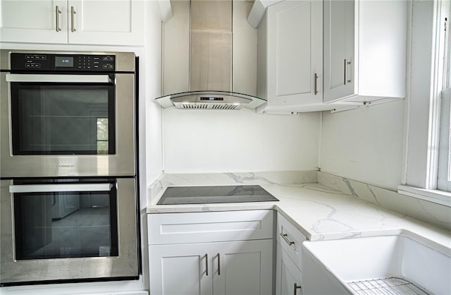 kitchen with ventilation hood, black electric stovetop, stainless steel double oven, and white cabinets