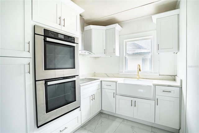 kitchen with black electric stovetop, double oven, sink, and white cabinets