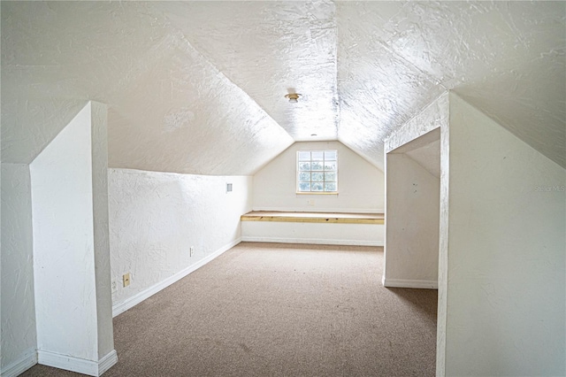 additional living space featuring lofted ceiling, carpet floors, and a textured ceiling