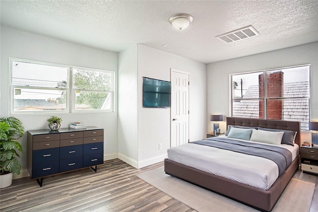 bedroom with light hardwood / wood-style floors and a textured ceiling