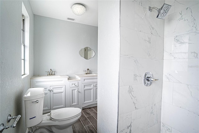 bathroom featuring tiled shower, vanity, and toilet