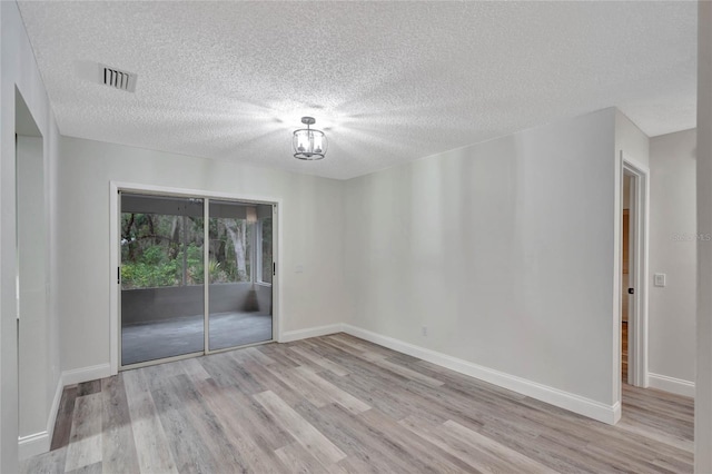 spare room featuring light hardwood / wood-style flooring and a textured ceiling