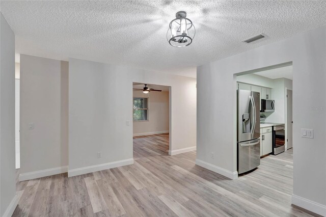 spare room featuring ceiling fan, a textured ceiling, and light wood-type flooring