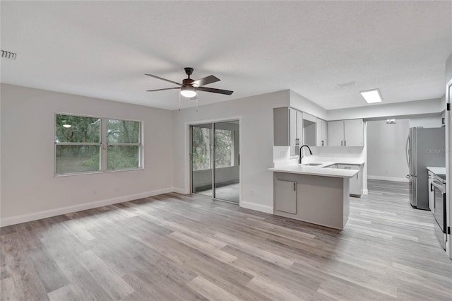 kitchen featuring sink, gray cabinetry, kitchen peninsula, stainless steel appliances, and a textured ceiling