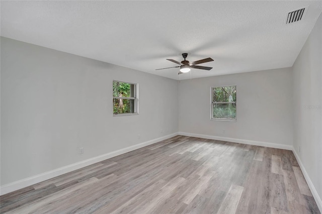 unfurnished room featuring a textured ceiling, light hardwood / wood-style flooring, and a healthy amount of sunlight