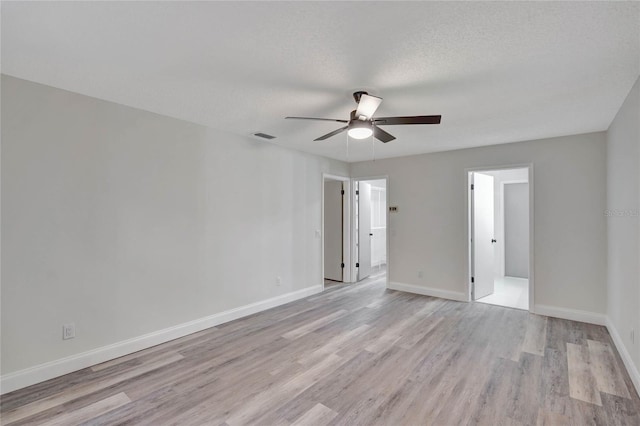 empty room with ceiling fan, light hardwood / wood-style floors, and a textured ceiling