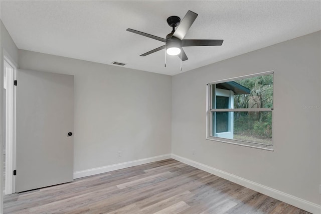 unfurnished room with ceiling fan, a textured ceiling, and light wood-type flooring