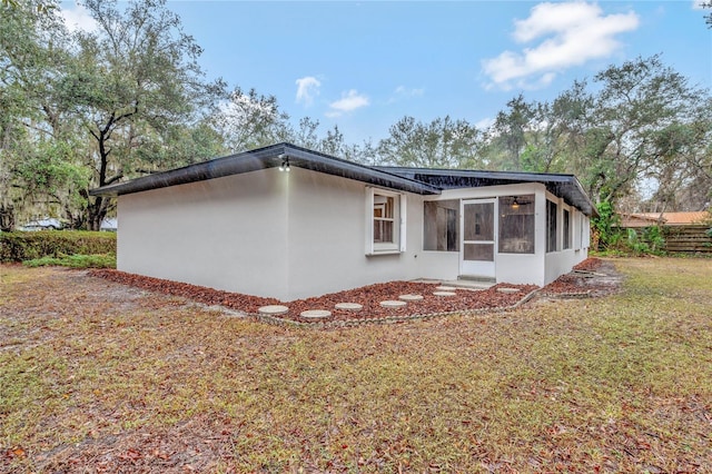 back of property with a yard and a sunroom