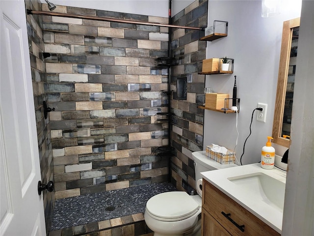 bathroom with a tile shower, vanity, and toilet