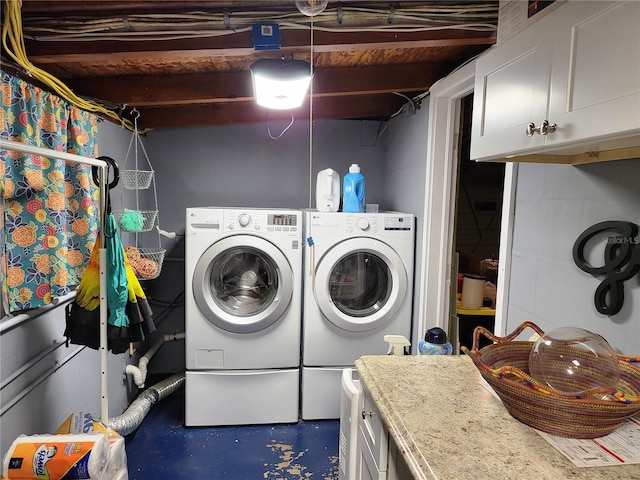 clothes washing area with cabinets and independent washer and dryer