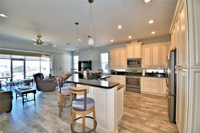 kitchen with a kitchen bar, decorative backsplash, hanging light fixtures, stainless steel appliances, and light hardwood / wood-style flooring