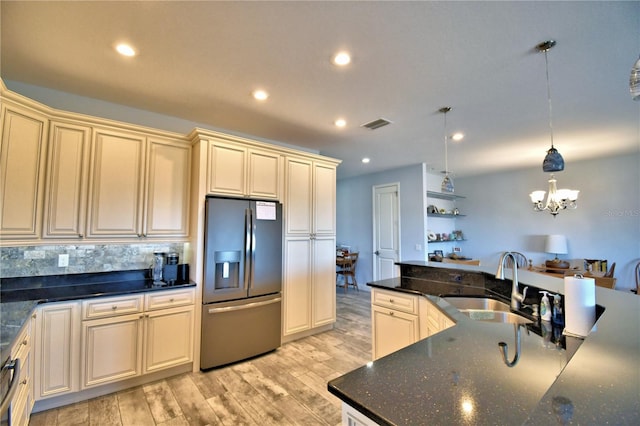 kitchen with pendant lighting, sink, cream cabinetry, and stainless steel refrigerator with ice dispenser