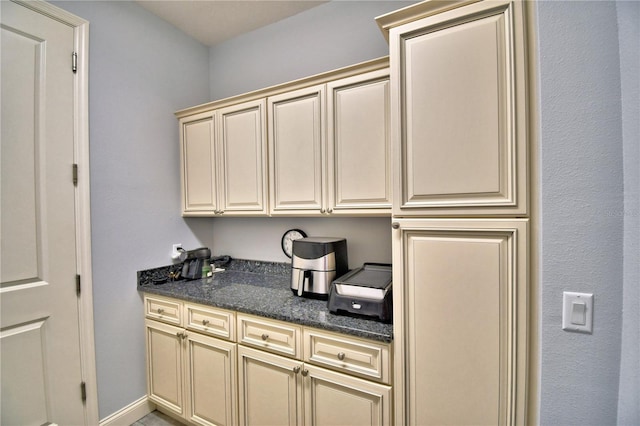 kitchen featuring dark stone counters and cream cabinetry