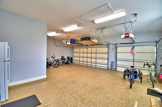 garage featuring white refrigerator and a garage door opener