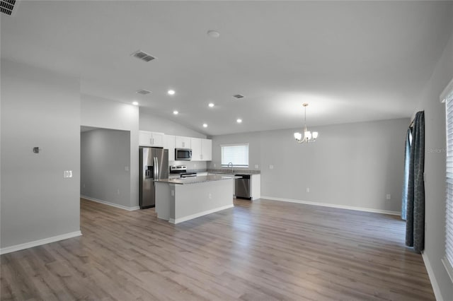 kitchen featuring appliances with stainless steel finishes, decorative light fixtures, white cabinetry, a center island, and a notable chandelier