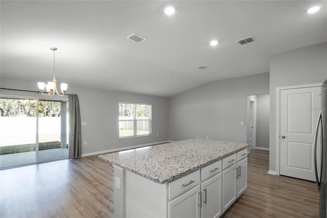 kitchen featuring white cabinetry, decorative light fixtures, a center island, and a wealth of natural light