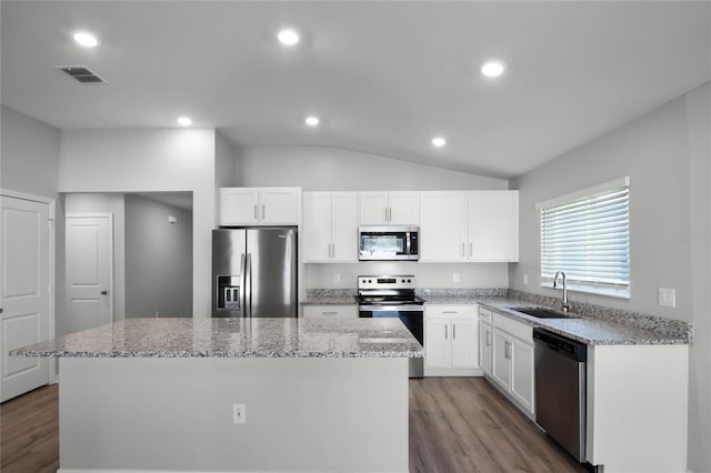 kitchen featuring sink, white cabinetry, appliances with stainless steel finishes, a kitchen island, and light stone countertops