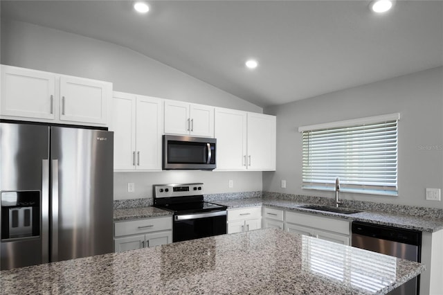 kitchen featuring lofted ceiling, sink, white cabinets, stainless steel appliances, and light stone countertops