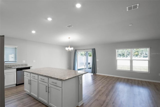 kitchen featuring a center island, white cabinets, decorative light fixtures, stainless steel dishwasher, and light wood-type flooring