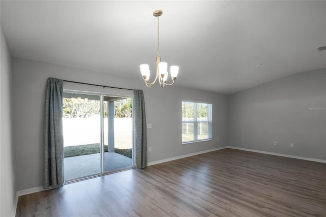 spare room with vaulted ceiling, hardwood / wood-style floors, and a notable chandelier