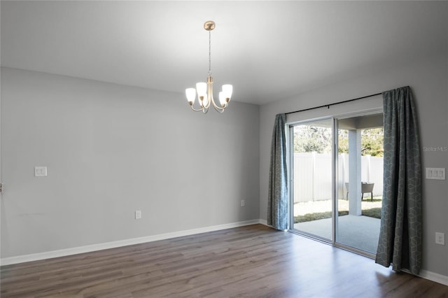 unfurnished room with an inviting chandelier and wood-type flooring