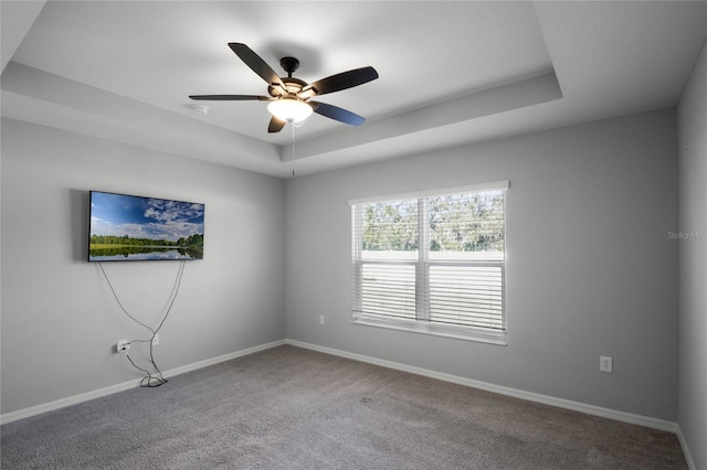 carpeted empty room with a tray ceiling and ceiling fan