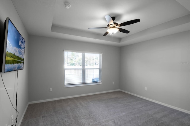 spare room featuring a tray ceiling, ceiling fan, and carpet flooring