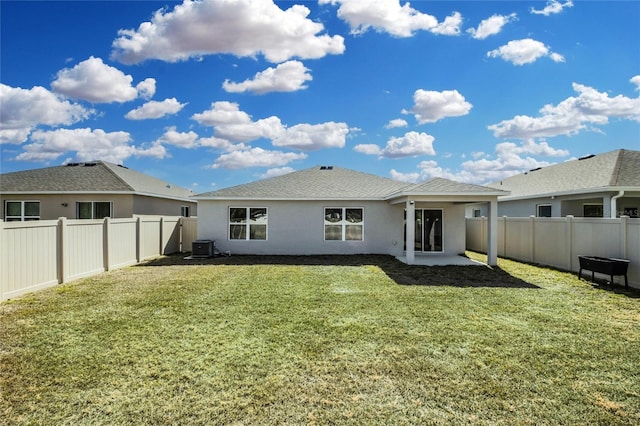 rear view of house with central air condition unit and a lawn