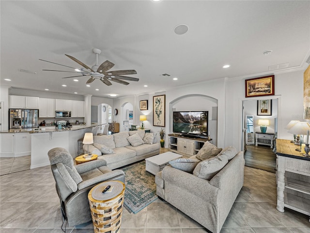 living room with ornamental molding, light tile patterned flooring, and ceiling fan