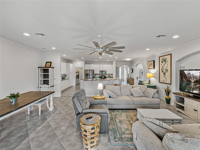 tiled living room featuring crown molding, ceiling fan, and washer / clothes dryer