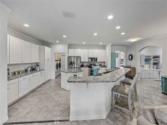 kitchen featuring a spacious island, white cabinetry, separate washer and dryer, stone counters, and stainless steel appliances